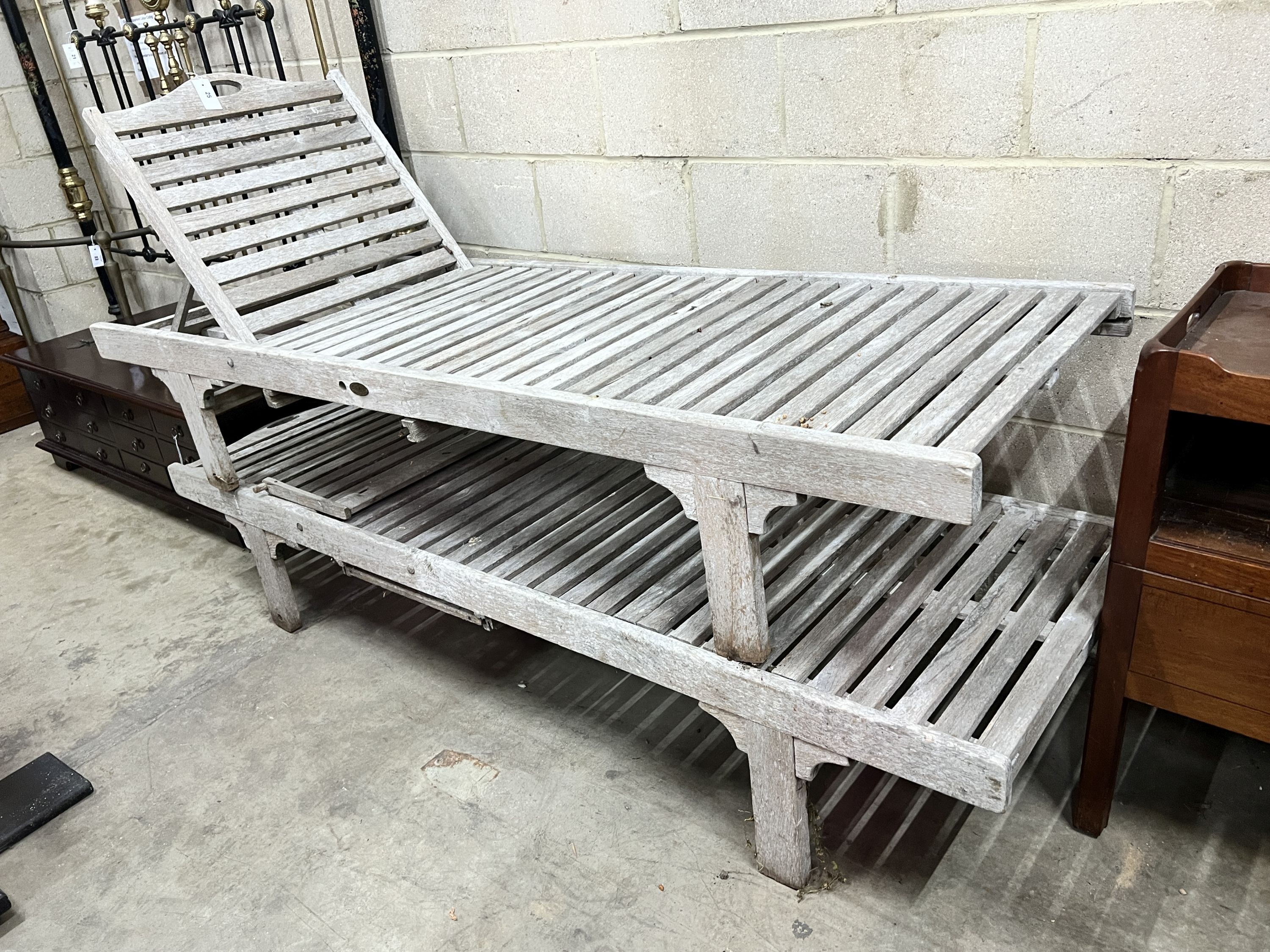 A pair of weathered teak garden loungers